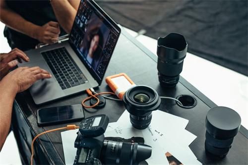 alt="Post-production setup with camera, lenses, and laptop"