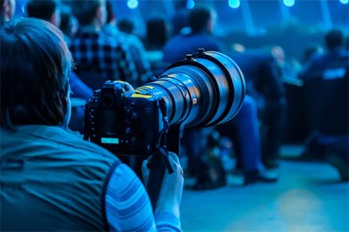 alt="Photographer with telephoto lens at an event"