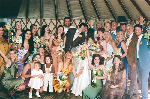 alt="Film-style group shot of a diverse wedding party with colorful dresses"