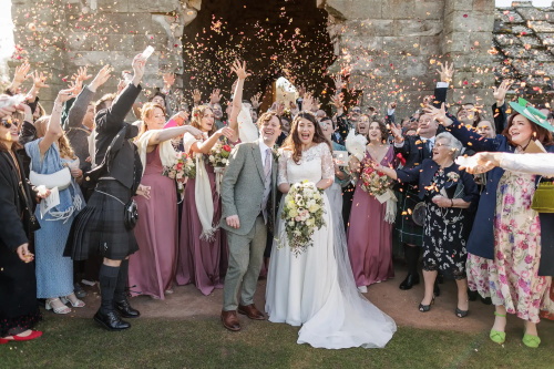 alt="Bride and groom celebrating with confetti at a Scottish wedding"