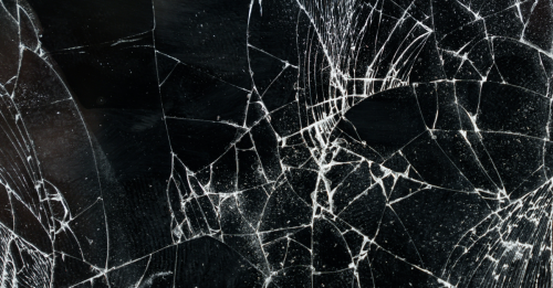 alt="Close-up of shattered glass on a black background"