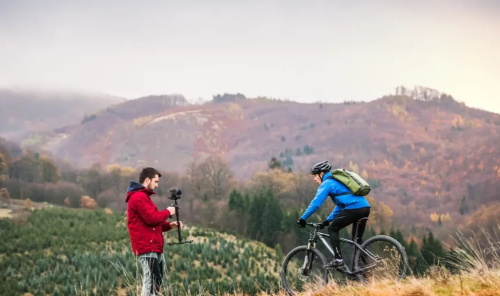 alt="Videographer shooting cyclist in hills"