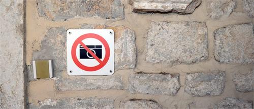 alt="No photography sign on stone wall"